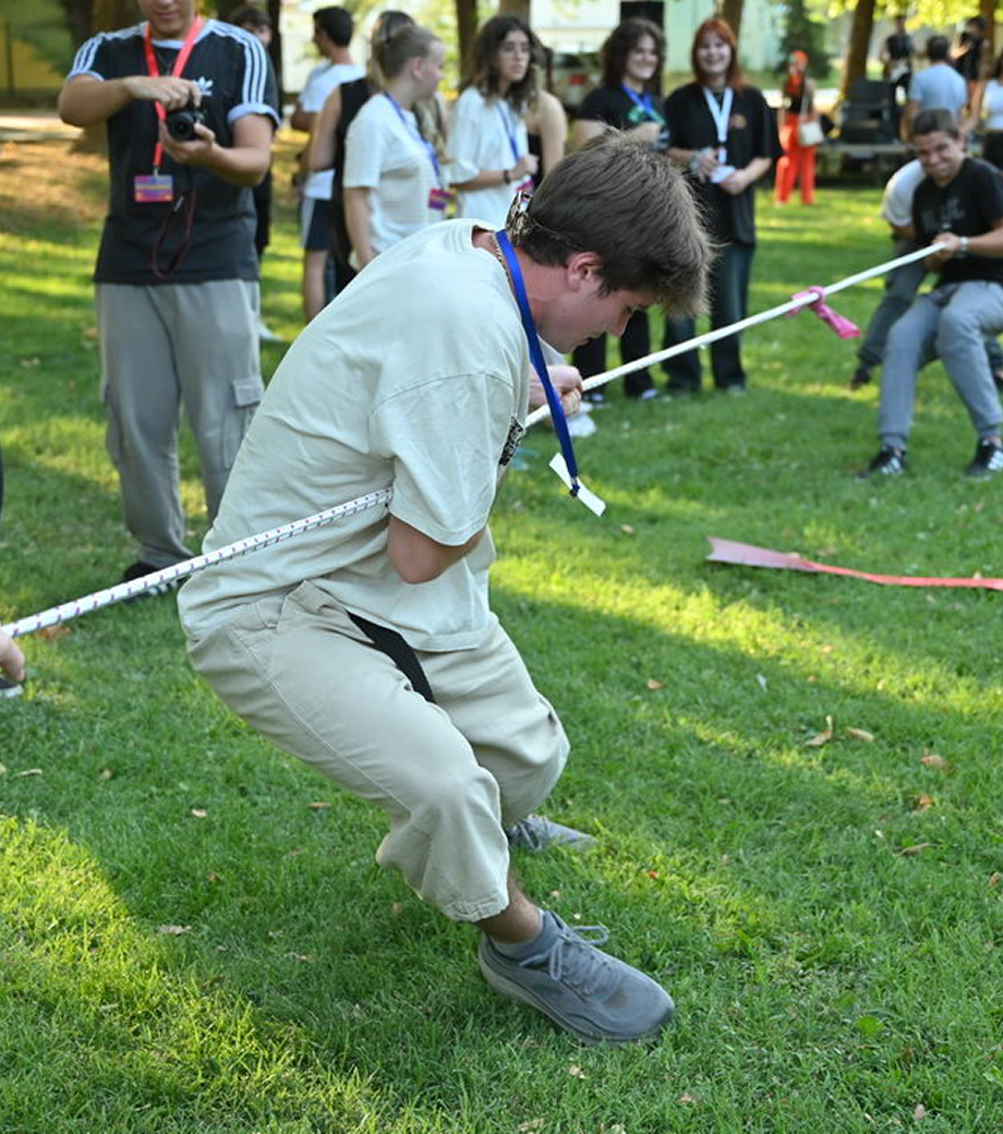 Two kids grappling on a rope with other youngsters in the background